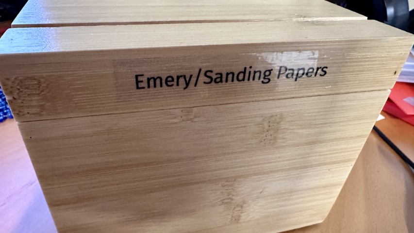 Outside of a bamboo box labeled "Emery/Sanding
Paper"
